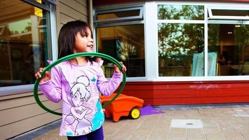 A young girl plays with a hula hoop outside