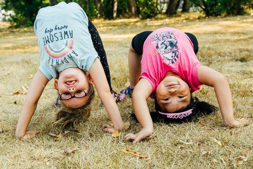 Two young girls doing handstands on the grass